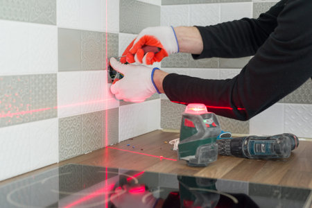Electrician using infrared laser level to install electrical outlets. Renovation and construction in...