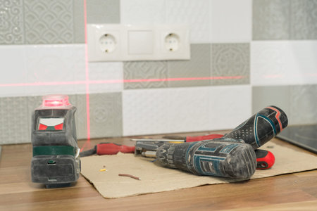 Electrician using infrared laser level to install electrical outlets. Renovation and construction in...
