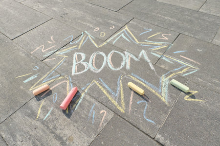 Text Boom drawing crayons on gray asphalt, top view