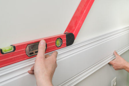 Closeup of gluing wooden white painted plank panel on wall, closeup, carpentry, woodwork,...