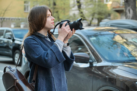 Beautiful young woman with camera in city. Tourist girl traveling and photographing, spring city...