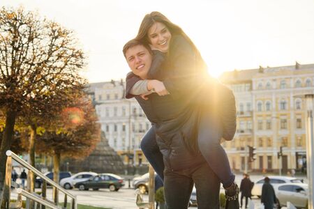 Couple of beautiful students are having fun in city, background spring city, young man and woman laughing, golden hour.の写真素材