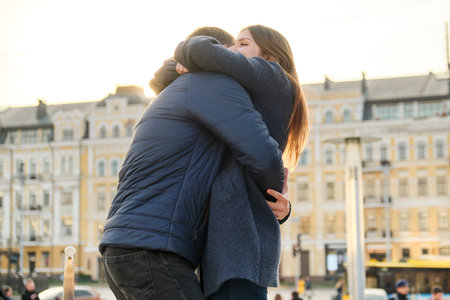 Young beautiful couple is embracing and having fun, romance in the spring city, golden hour.
