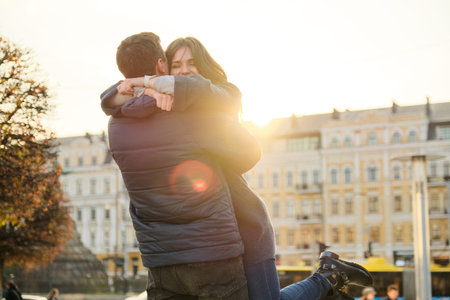 Young beautiful couple is embracing and having fun, romance in the spring city, golden hour.