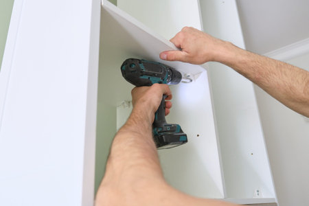Installation of furniture. Closeup of workers hand with professional tools and furniture details.