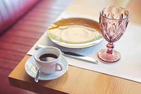 Coffee in white cup and saucer on table in cafe, the table is served with dishesの写真素材