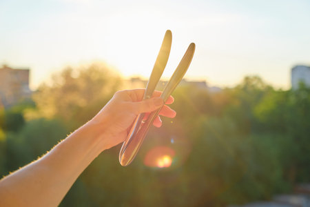 Two steel metal shiny knives in womans hand, background sunset, evening city