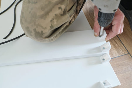 Furniture assembly. Closeup of workers hand with professional tools and furniture details