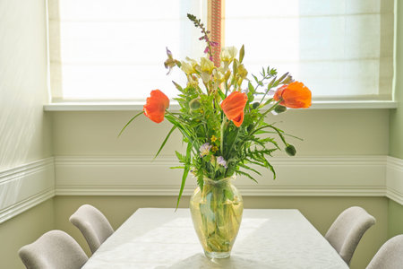 Bouquet of spring summer flowers and red poppies in vase, standing on table in living room, dining...