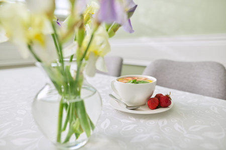 Strawberry tea with mint lemon berries on table close-up. Table near the window with vase of irises...