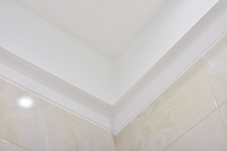 Bathroom, ceiling with moldings, beige tiles on the wall.の写真素材
