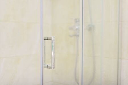 Shower, bathroom interior, light beige color, glass door with chrome handle close-upの写真素材