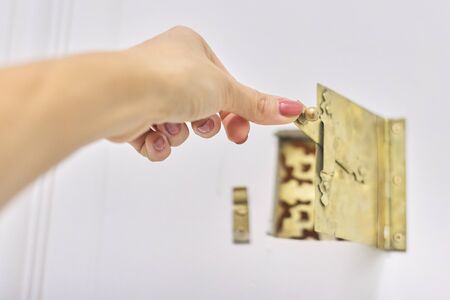 Vintage antique metal golden peephole in front door, woman hand opening peephole latchの写真素材
