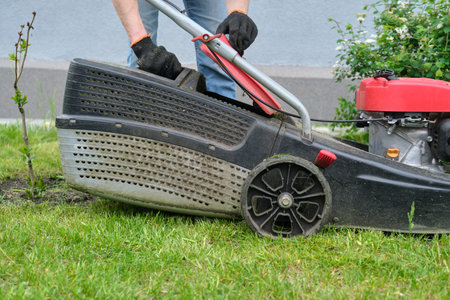Working lawn mower on green lawn with trimmed grass.