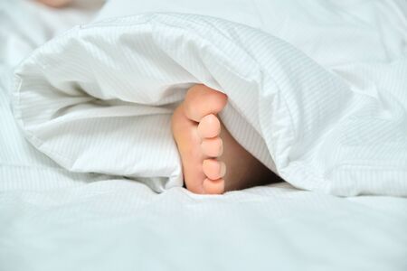 Bare foot of young woman sleeping in white bed, healthy sleep.の写真素材