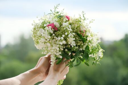 Close-up bouquet of fresh flowers rose and lily of the valley in woman hand. Springtime, holidays, wedding, beautyの写真素材