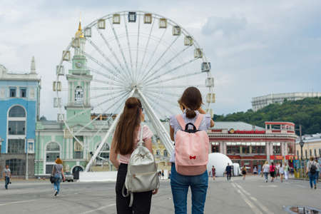 Kyiv UA, 19-07-2018. Young teenage girls are walking the streets of the city. Background Ferris wheel, square of the European city, view from the bac.のeditorial素材