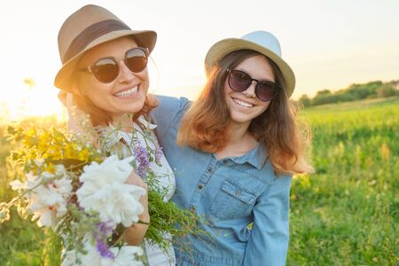 Summer portrait of happy mother and daughter on the nature in the meadow, golden hour.の写真素材