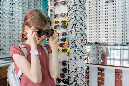 Little buyer in the glasses store, girl child chooses sunglasses.の写真素材