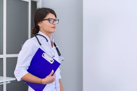 Portrait of young female medical doctor with stethoscope clipboard at hospital, copy spaceの写真素材