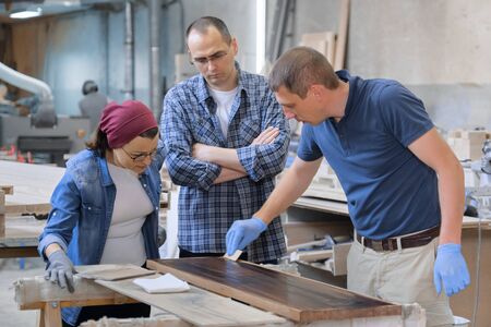 Workers in carpentry woodworking workshop, varnishing wooden plank with oil.の写真素材