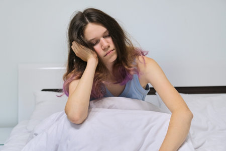 Teen girl sleeping at home in bed, morning asleep sitting.