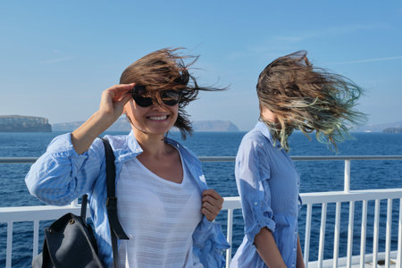 Two women enjoying sea travel on cruise ship, hair flying in the wind.