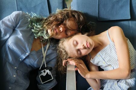 Tired sleeping children in passenger seat in vehicle. Two tourist girls sleeping on trip.の写真素材