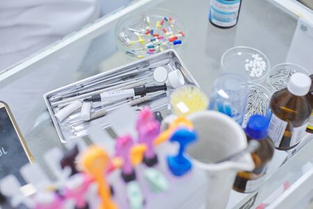 Close-up work at dentist doctor desk, dental composite sealing materials resins, professional dental instruments tools and medicines. Technology, medicine, care and dental health.の写真素材