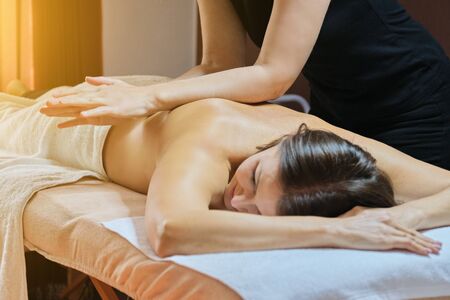 Professional back massage procedure, adult woman receiving treatment lying on massage tableの写真素材