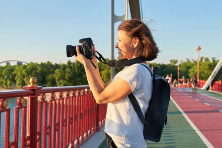 Mature woman photographing with camera. Woman photo journalist, travel blogger, middle-aged female hobby photoの写真素材