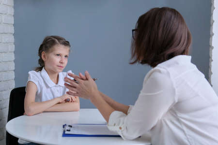 Communication session of school psychologist and girl 9, 10 years. Child tells psychotherapist his experiences, mental health of childrenの写真素材