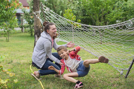 Child girl falling from hammock, spring garden background, having fun laughing girlsの写真素材