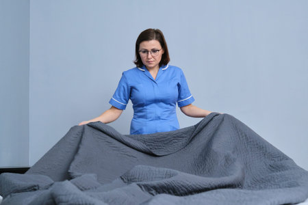 Chambermaid making guest bed in hotel bedroom. Service, cleaning, staff, hotel concept