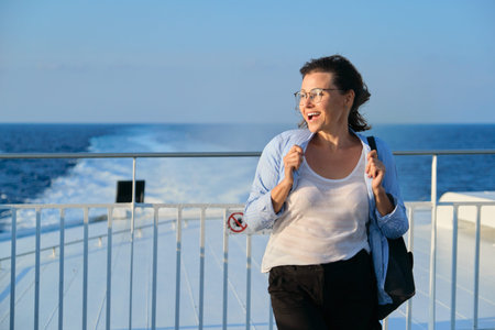 Woman on deck of ferry, female standing in strong wind, enjoying sea travel, sunset at sea, copy...
