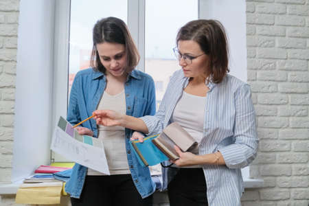 Two women interior designer and client choosing fabrics for home textile decoration, curtains, furniture upholsteryの写真素材