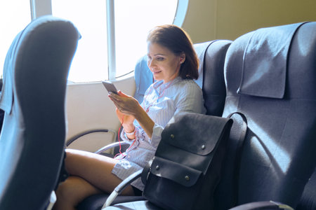 Passenger of sea ferry mature woman traveling in cabin of boat. Female sitting on armchair resting,...