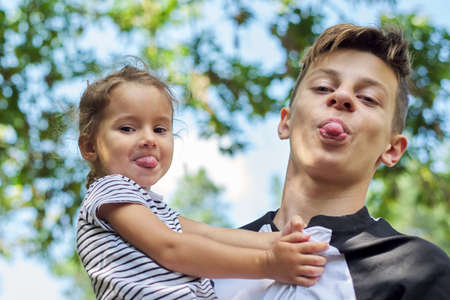 Children boy teenager and toddler girl look at the camera and show tongues.の写真素材
