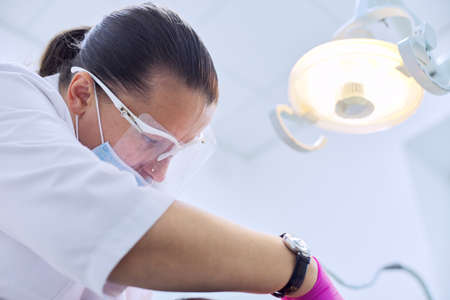 Experienced dentist treats teeth in patient. Technology, medicine, care and dental health.の写真素材