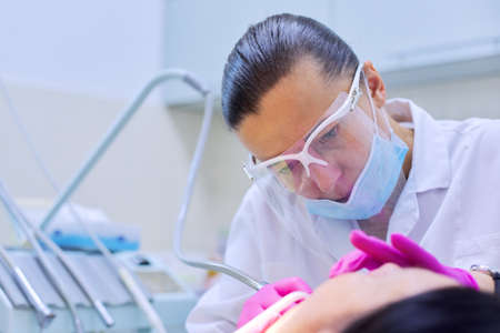 Experienced dentist treats teeth in patient. Technology, medicine, care and dental health.の写真素材