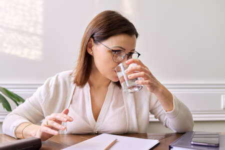 Businesswoman, teacher, psychologist drinking water from glass, close-up face. Portrait of woman taking headshotの写真素材