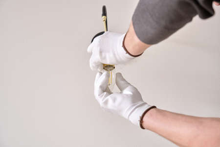 Close-up hands of electrician installing wall lamp.の写真素材
