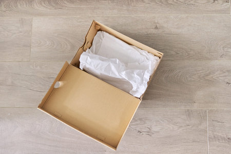 Empty cardboard box from shoes on the floor in the house, top view.