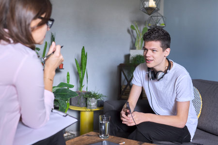 Teenage boy at meeting with female professional doctor psychologist. Adolescent counseling help, school psychologist, child social worker, adolescent problemsの写真素材
