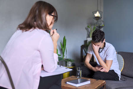 Teenage boy at meeting with female professional doctor psychologist. Adolescent counseling help, school psychologist, child social worker, adolescent problems