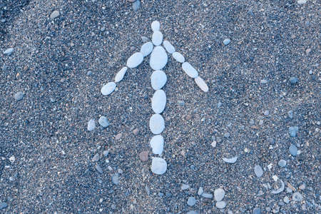 Arrow forward concept, arrow lined with white pebbles on black sea pebbles.の写真素材