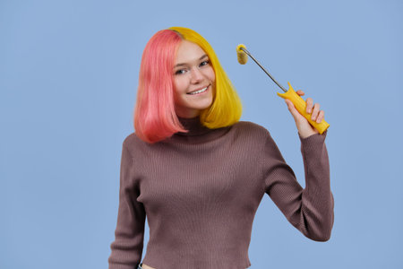 Beautiful girl dyes her hair with construction roller, teenager with fashionable colored yellow pink...