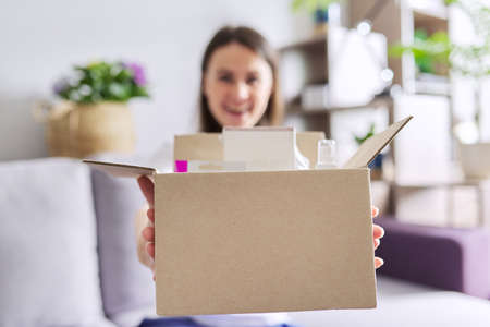 Close-up of box with online shopping in hands of happy young woman, internet shopping, parcel delivery service, empty space for text on cardboardの写真素材