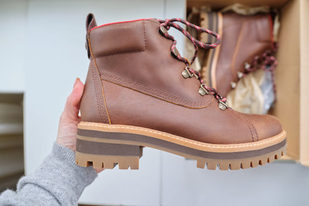 New womens leather brown waterproof hiking winter autumn boots in hands of female, trendy footwear...