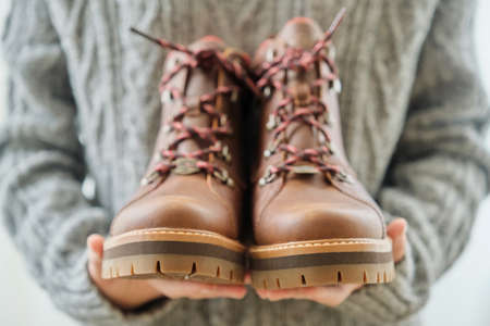 New womens leather brown waterproof hiking winter autumn boots in hands of female, trendy footwear for winter. Unpacking shoes, shopping online from home, shoe fashion storeの写真素材